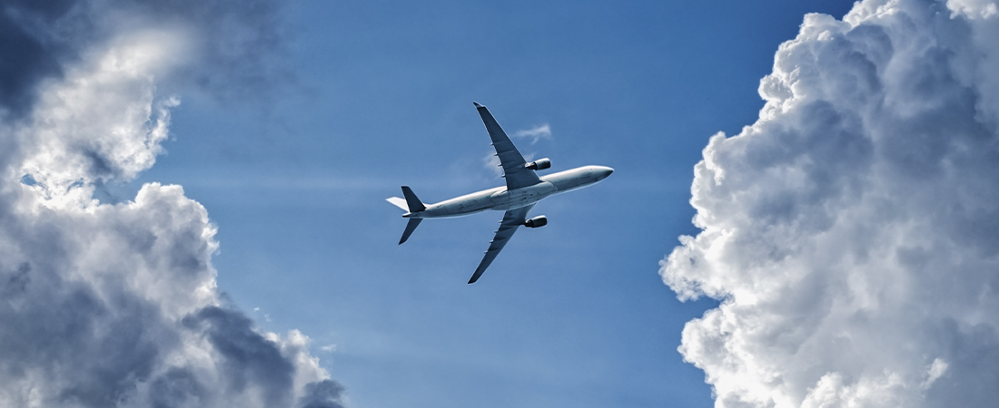 Avión de pasajeros volando en un cielo azul entre nubes blancas densas.